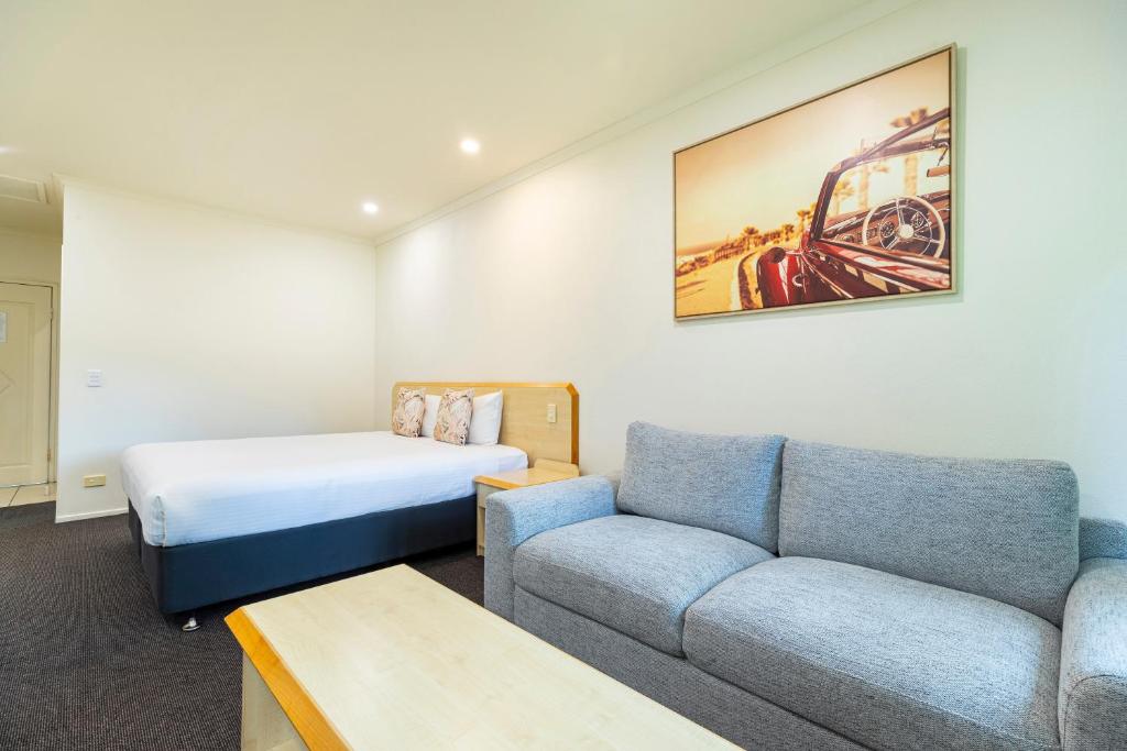 a hotel room with a couch and a bed at Red Bridge Motor Inn in Woombye