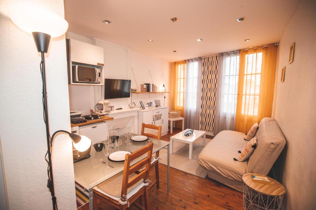 une cuisine et un salon avec une table et un canapé dans l'établissement Cocooning studio Rue Raphaël, au Puy-en-Velay