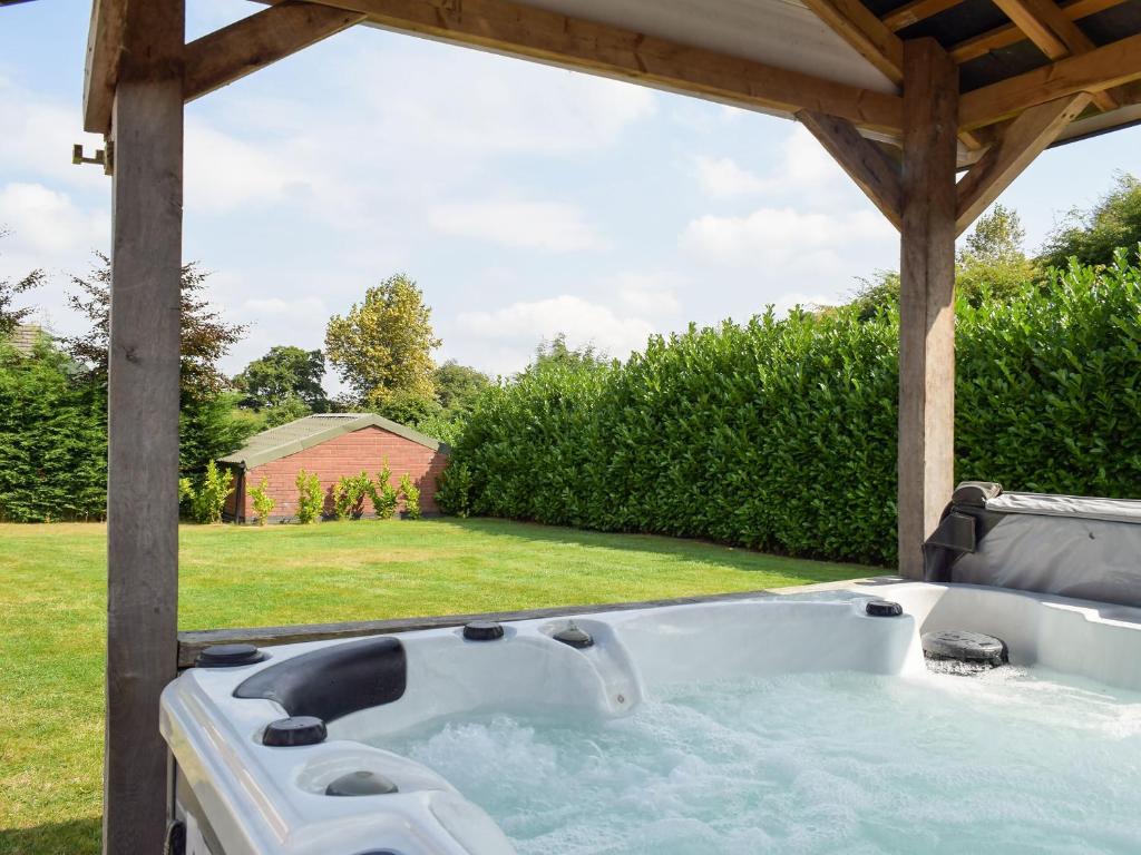una bañera de hidromasaje bajo una pérgola en un patio en River Cottage, en Llangunllo