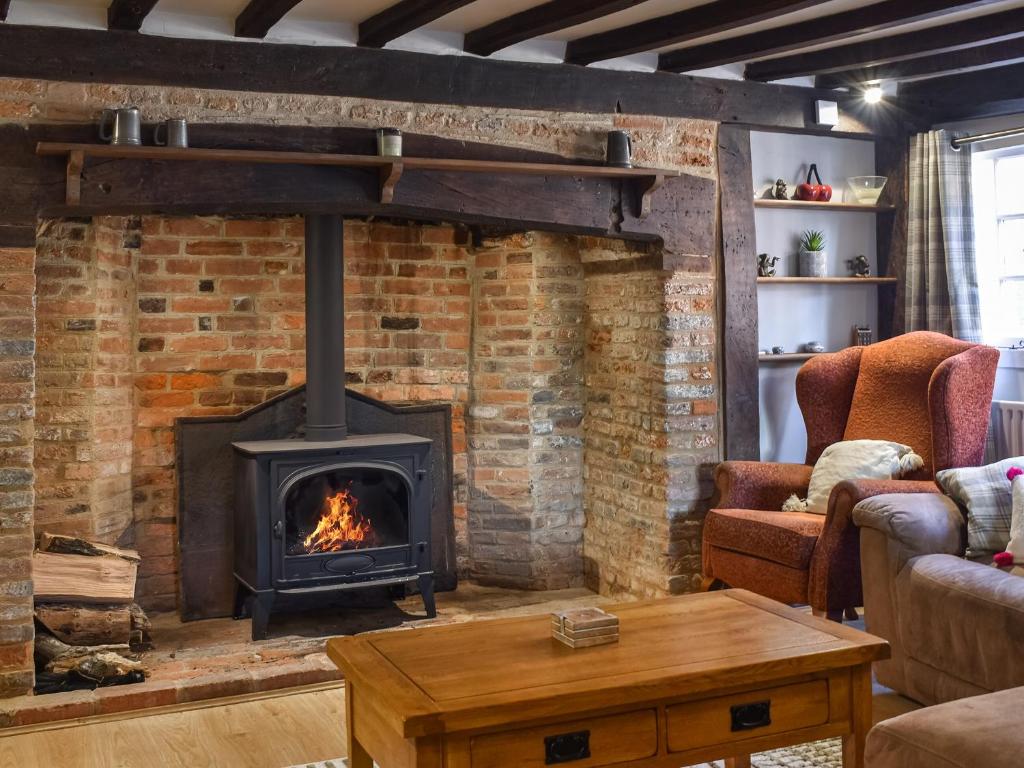 a living room with a brick fireplace at Rose Cottage in Bethersden