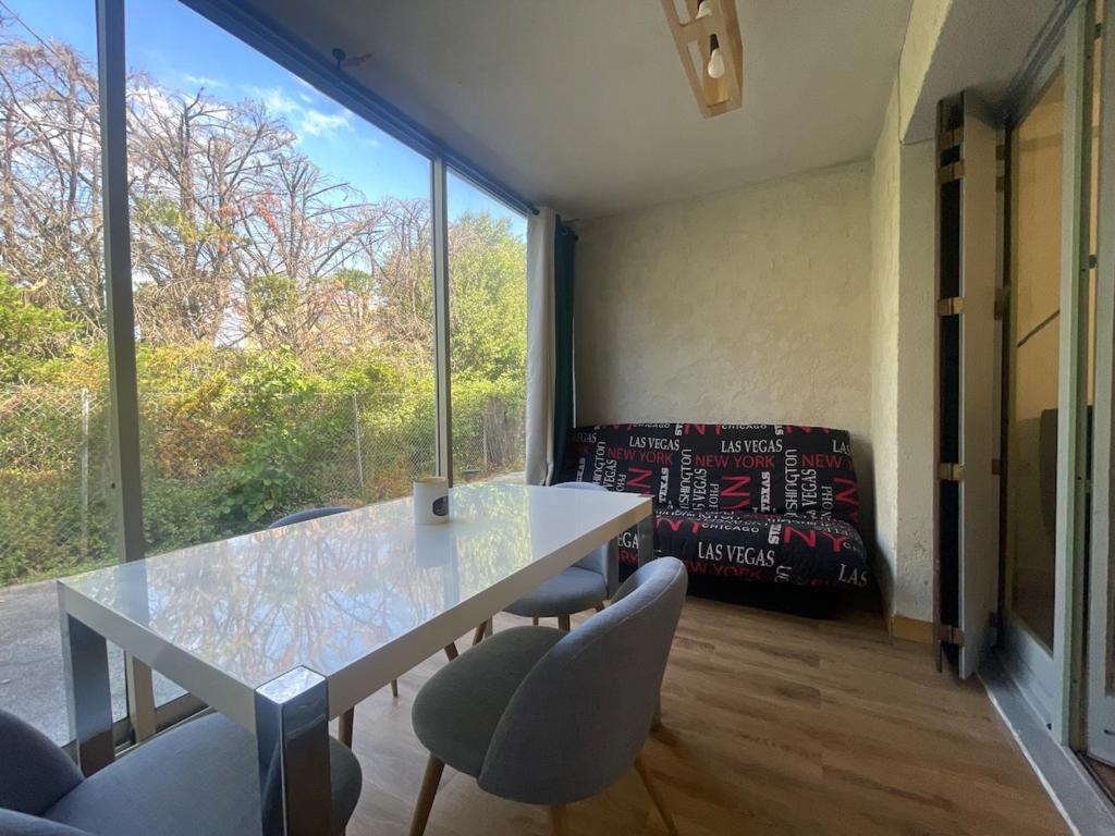 une table et des chaises dans une pièce avec une grande fenêtre dans l'établissement Cozy Gardeen Studio, à La Garde