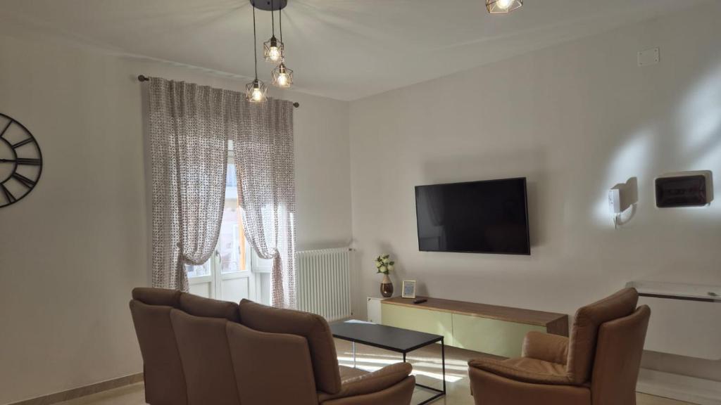 un soggiorno con sedie, tavolo e TV di Casa Antonini a L'Aquila