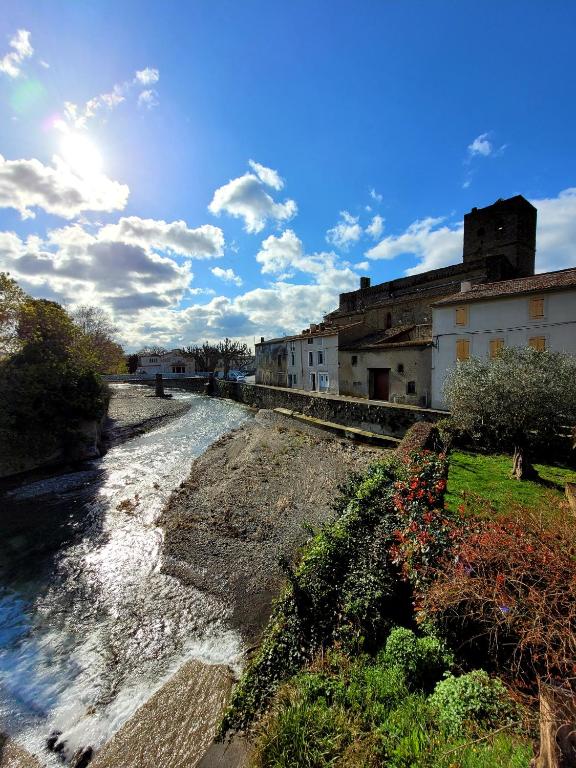 une rivière dans une ville avec un bâtiment dans l'établissement Le Refuge, à Peyriac-Minervois