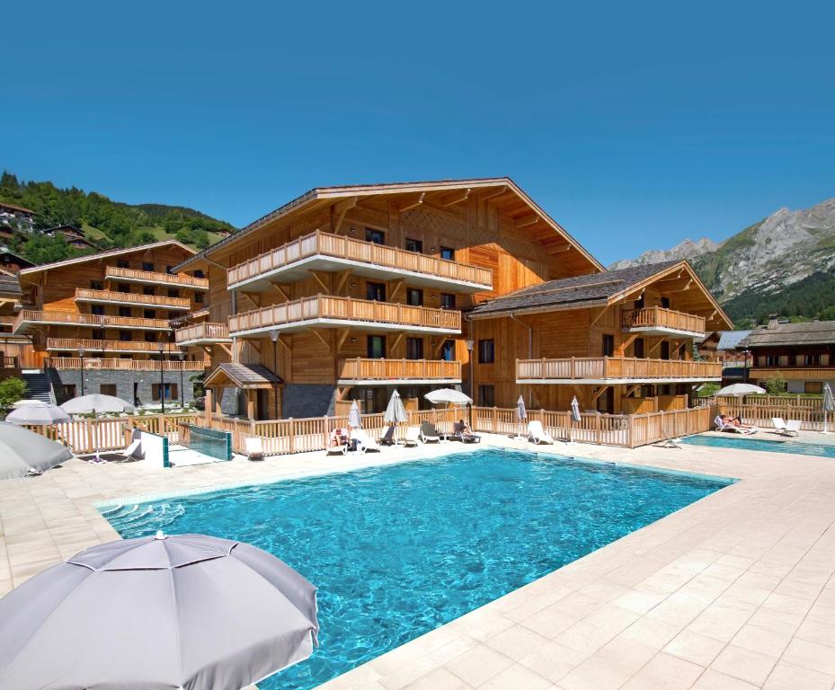 un hôtel avec une piscine devant un immeuble dans l'établissement Résidence Prestige Odalys Mendi Alde, à La Clusaz