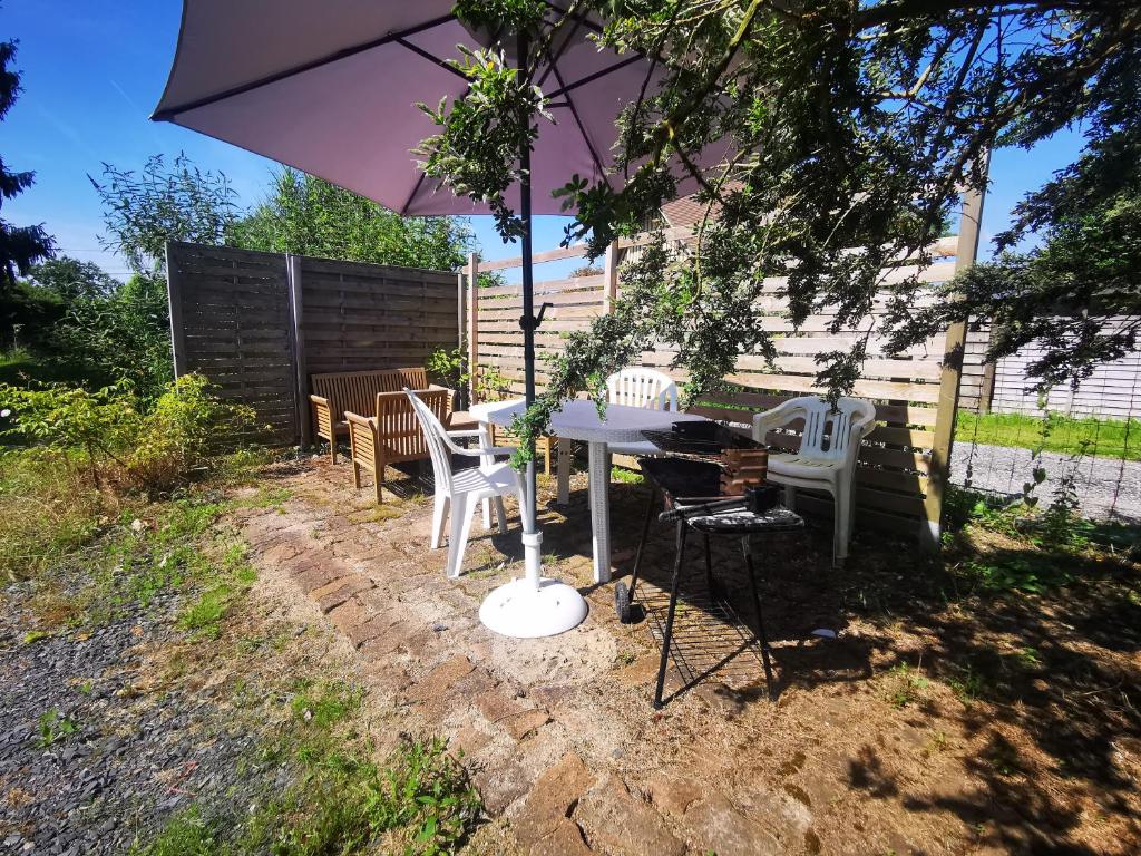 - une table et des chaises sous un parasol dans la cour dans l'établissement Les grands pins, à Fiquefleur-Équainville