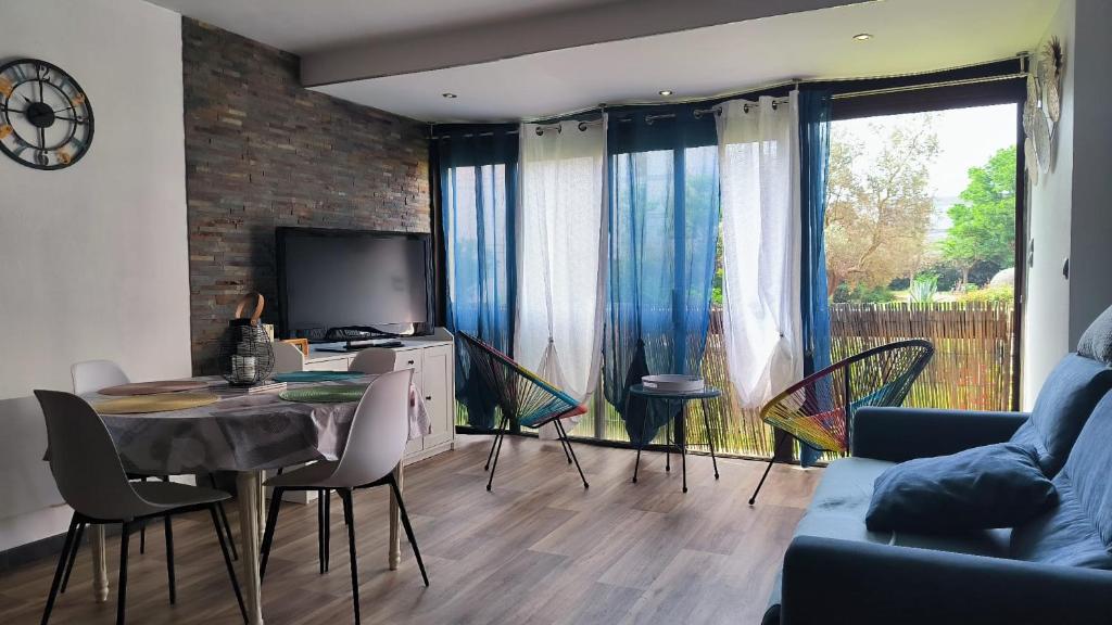un salon avec une table, des chaises et une télévision dans l'établissement St Cyprien appartement lumineux proche plage, à Saint Cyprien Plage