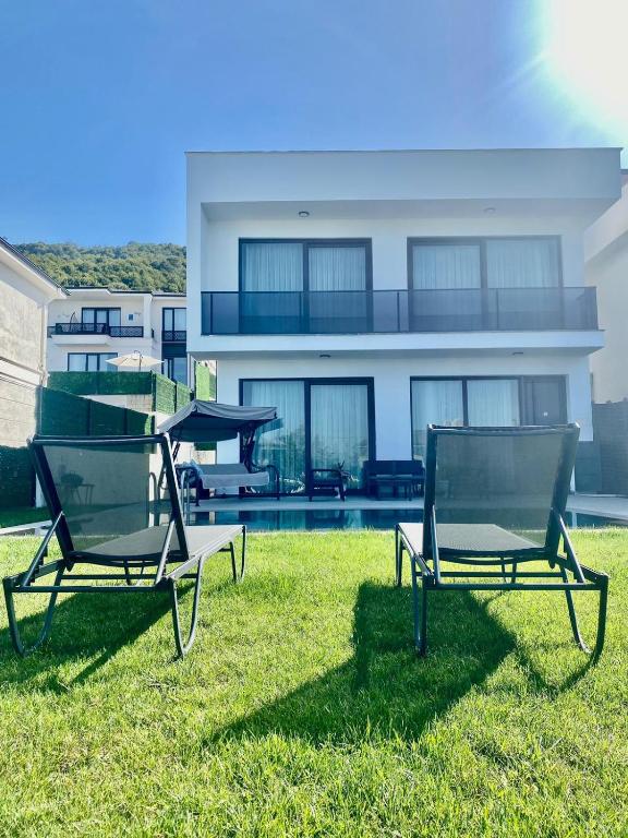 two chairs sitting in the grass in front of a house at High Garden Villas in Sapanca