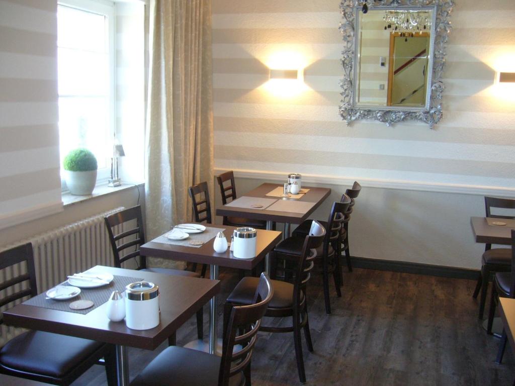 a restaurant with wooden tables and chairs and a mirror at Hotel Theile garni in Gummersbach