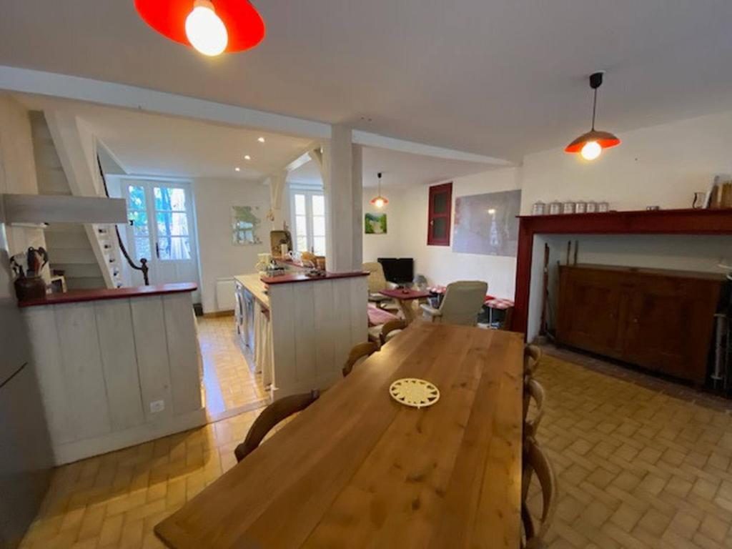 a living room with a wooden table and a kitchen at Jolie maison de vacances centre Gramat in Gramat