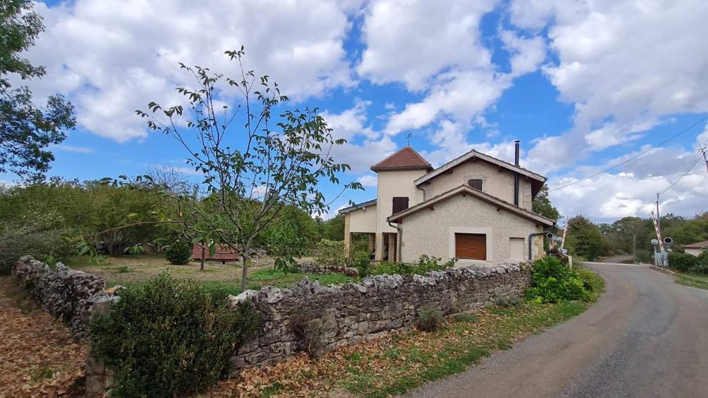 a house with a stone wall next to a road at Maison de campagne au Touleyrou in Issendolus
