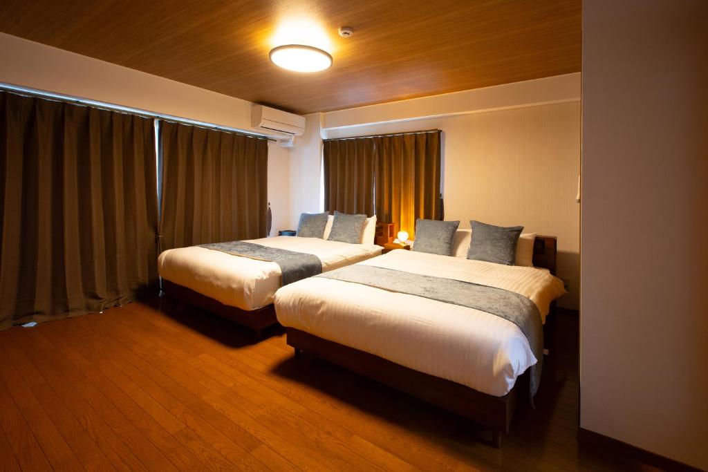 a hotel room with two beds and a window at エレガンス表町-市内中心部でアクセス良好 ワンフロア貸し切りでパーティもOｋ駐車料金無料 in Okayama