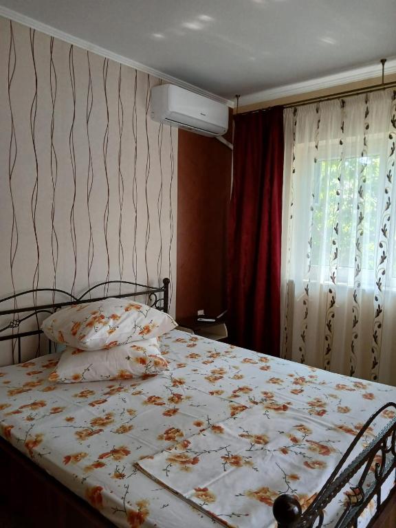 een slaapkamer met een bed met een wit dekbed en een raam bij Vila cu Flori in Eforie Sud