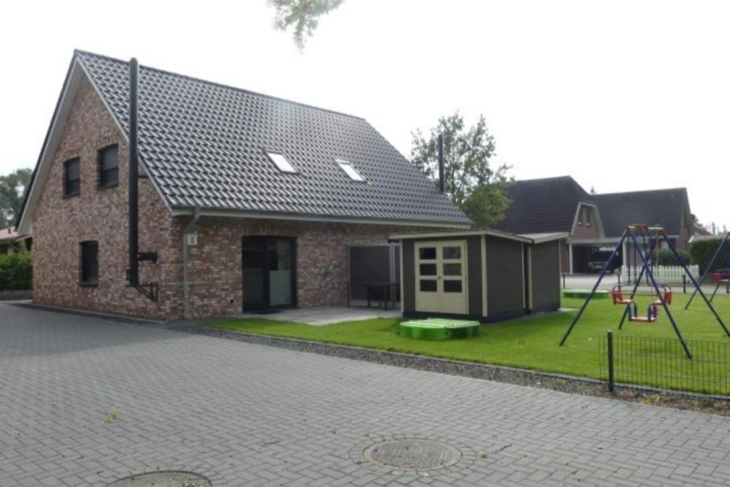 a house with a playground in the yard at 6 Personen Ferienhaus mit Sauna, Whirlpool, zwei Duschen sowie Kaminofen in Otterndorf in Otterndorf