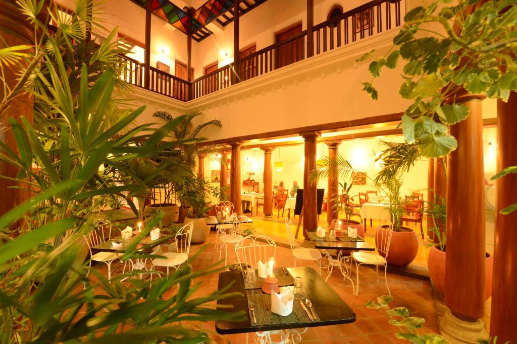 een grote lobby met tafels, stoelen en planten bij Maison Perumal Pondicherry - CGH Earth in Pondicherry