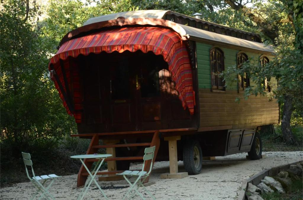 a tiny house sitting on a table with chairs at La Roulotte Authentique in Grignan