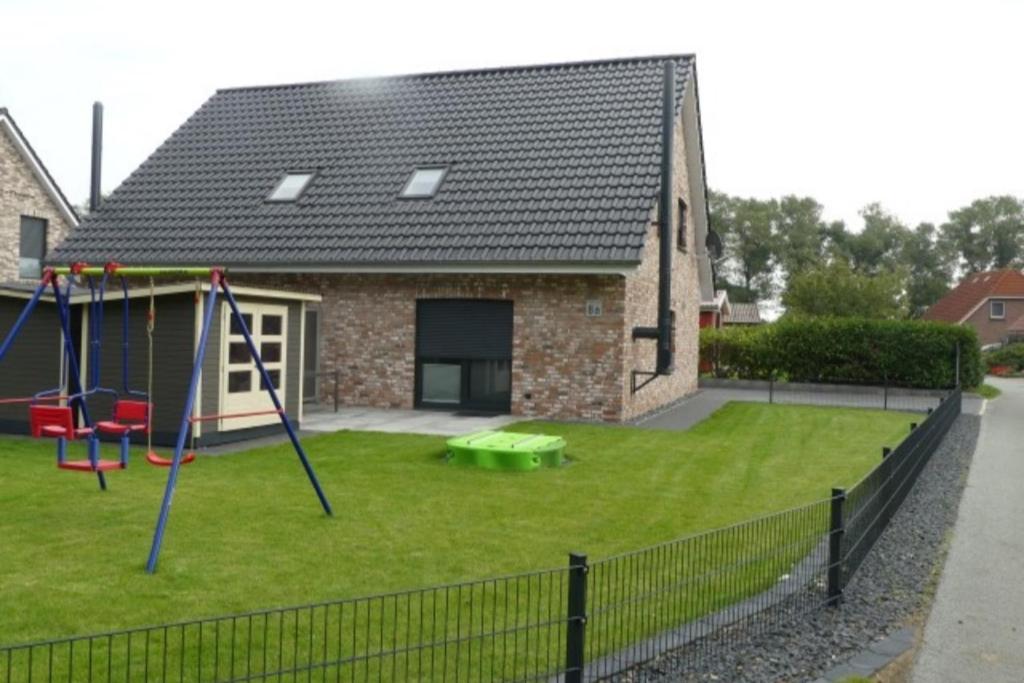 a yard with a playground in front of a house at 6 Personen Ferienhaus mit zwei Duschen und Toiletten, Sauna, Whirlpool und Kaminofen in Otterndorf in Otterndorf