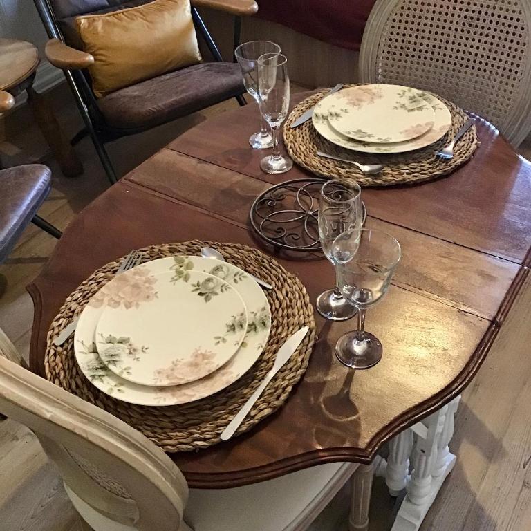 une table en bois avec deux assiettes et des verres dans l'établissement Studio 23m2 Le Grand Hotel en hyper centre-ville avec balcon, à Aix-les-Bains