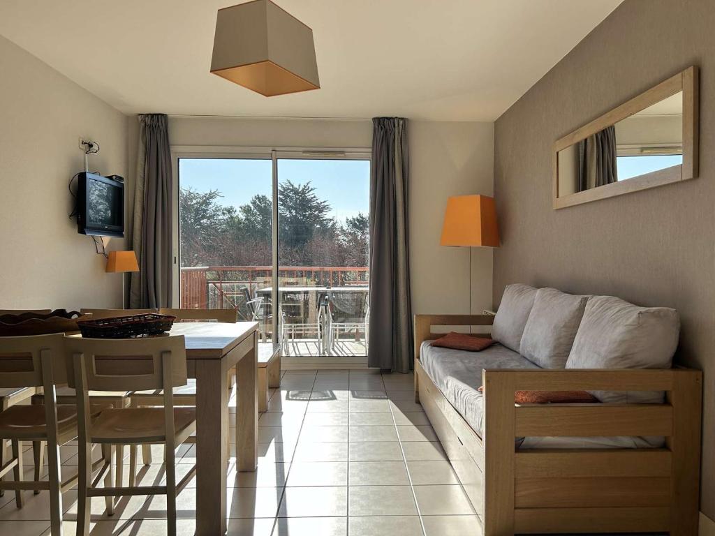 un salon avec un canapé et une table et une cuisine dans l'établissement 100 - Appart duplex 6p avec piscine collective., à Fréhel