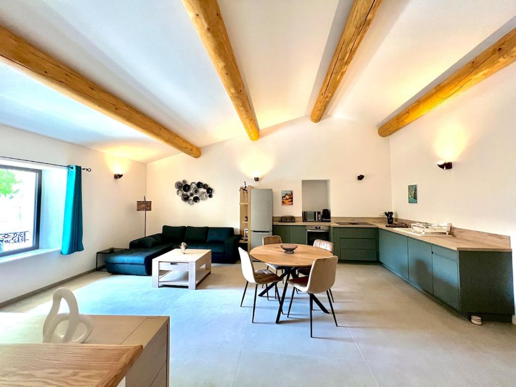 a kitchen and living room with a table and chairs at La tanière d'Agoult in Goult