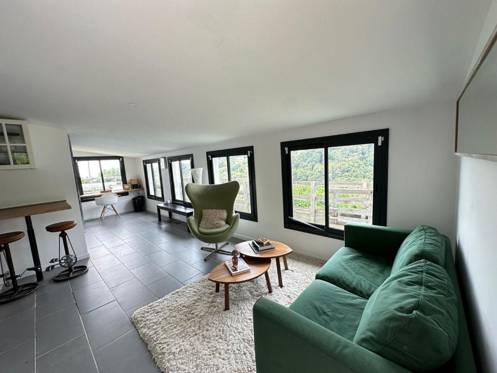 un salon avec un canapé vert et une table dans l'établissement Quiet in nature - Nice, à Nice