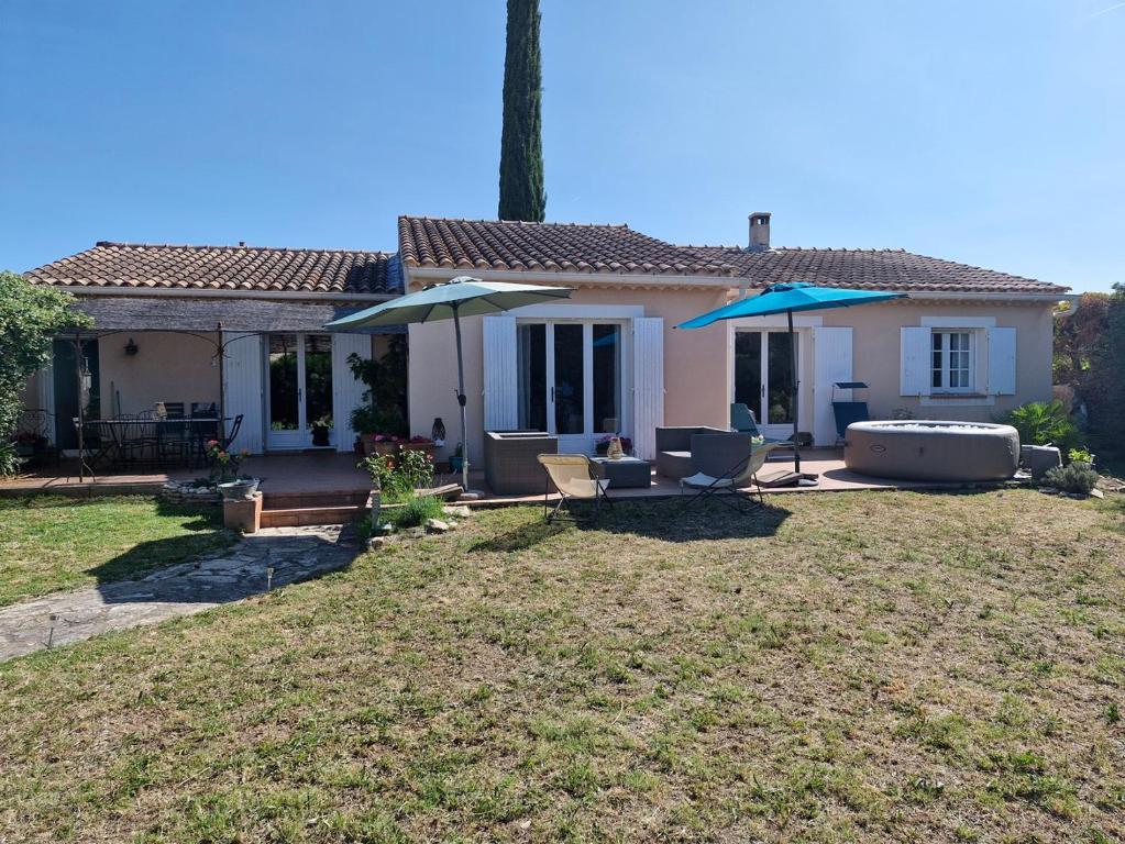 une maison avec une cour dotée de chaises et de parasols dans l'établissement Villa avec jacuzzi au cœur de la Provence !, à Monteux