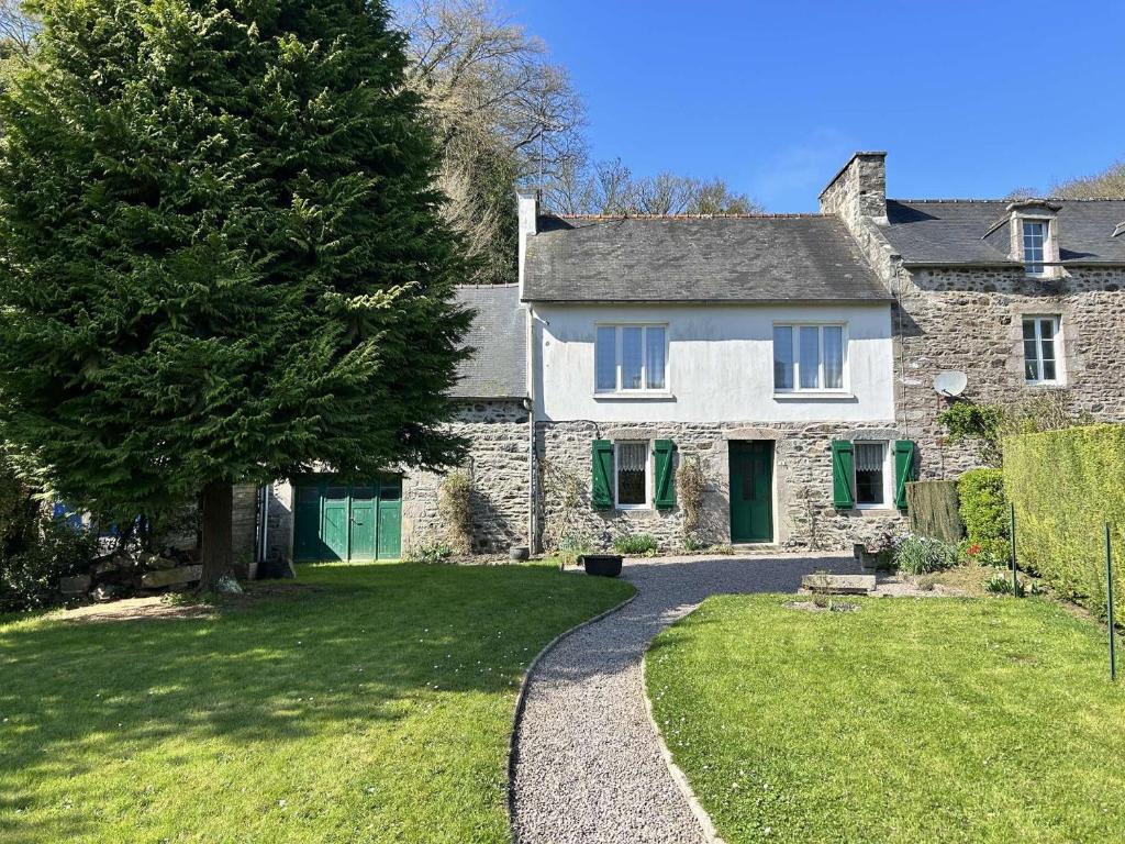 une maison en pierre avec un arbre et une allée dans l'établissement 309 - Charmante maison familiale au cœur du village de Port-à-La-Duc, à Fréhel