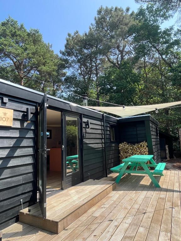 a black tiny house with a picnic table on a deck at Bumblebee Cabin met privé sauna & vuurplaats in Diessen