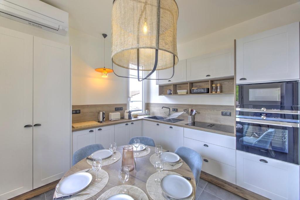 a kitchen with white cabinets and a table and chairs at Le Banc de Sable - A 5 min de la plage in Arcachon