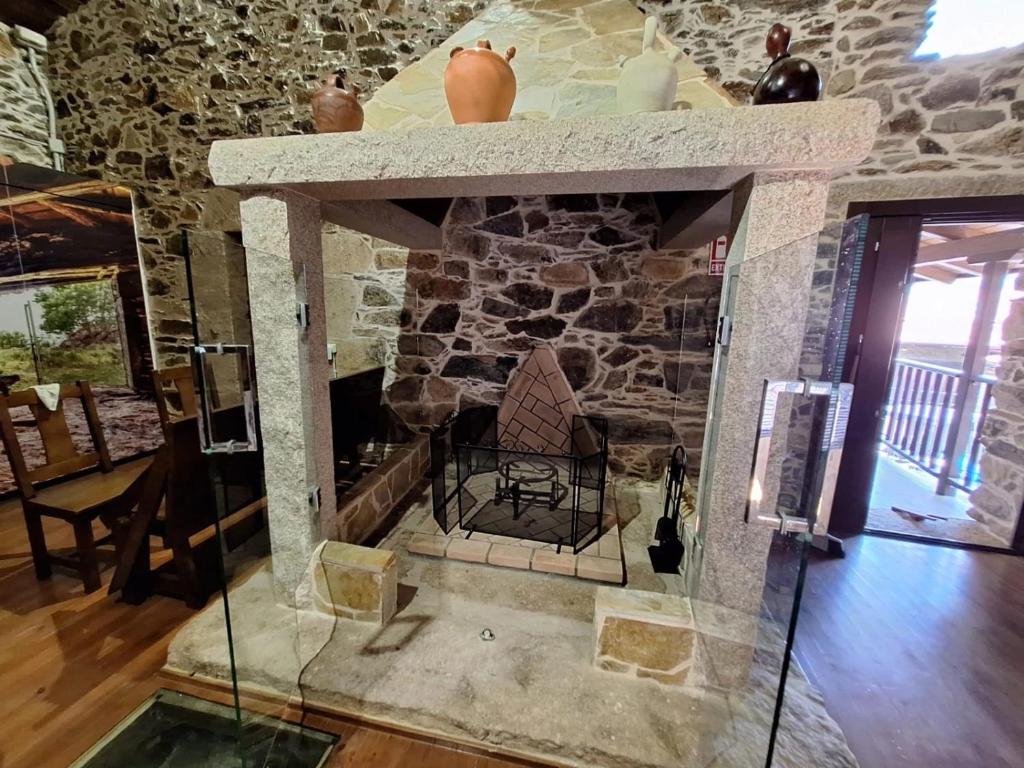 einen Kamin in einem Zimmer mit einer Steinmauer in der Unterkunft Casa Vacacional Familia Ferro in Cartelle
