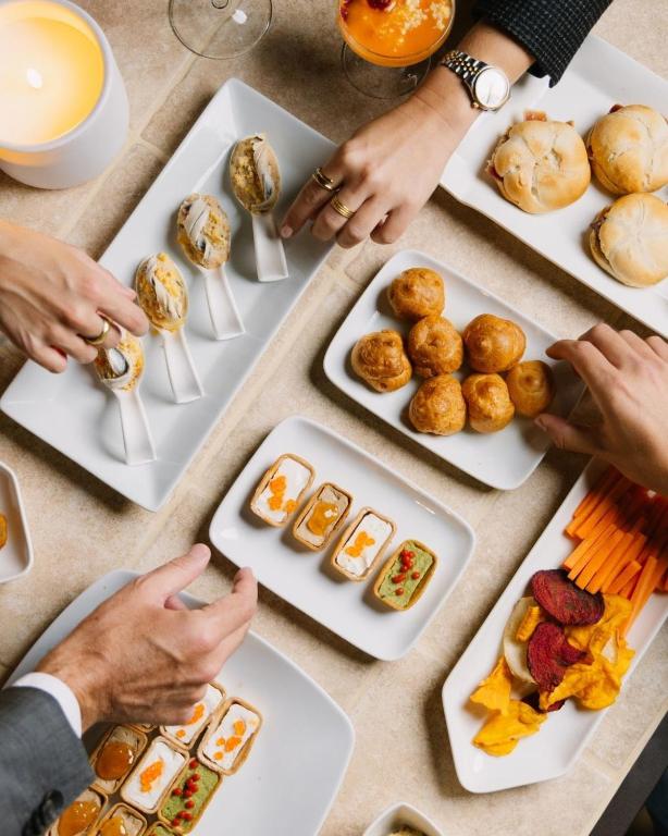 a group of people reaching for food on plates at Melia Plaza Valencia in Valencia