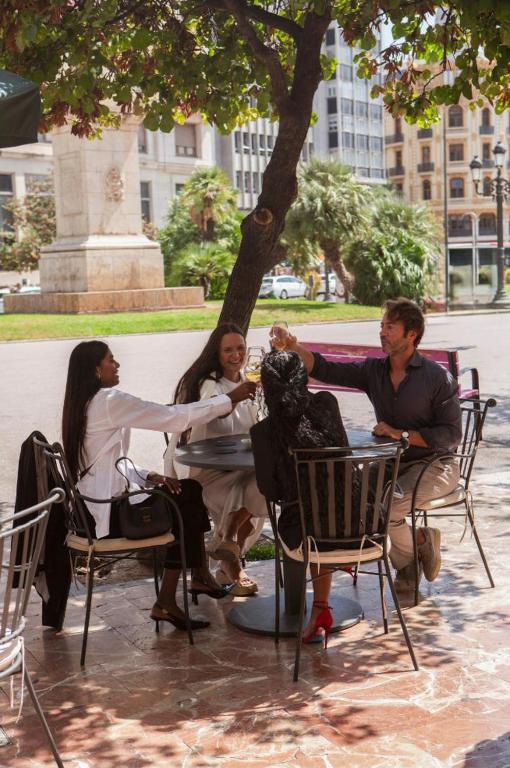 a group of people sitting in chairs under a tree at Melia Plaza Valencia in Valencia