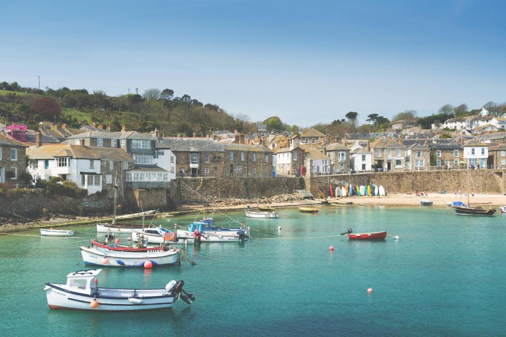 a group of boats in a body of water with houses at The Ship Inn in Mousehole