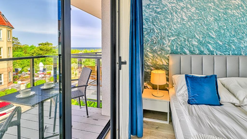 a bedroom with a balcony with a bed and a table at Rezydencja Niechorze 306 z Widokiem na Morze - 5D Apartments in Niechorze