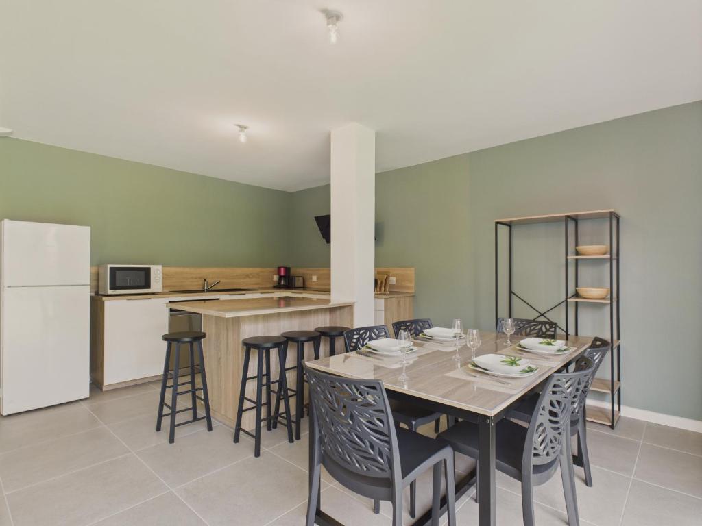 ein Esszimmer mit Tisch und Stühlen und eine Küche in der Unterkunft Jardin clos - Maison de plain-pied pour 4 in Le Tour-du-Parc