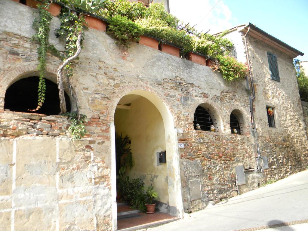 um antigo edifício de pedra com um arco e plantas nele em Casa David em Calci