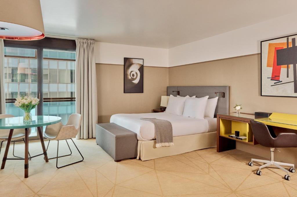 une chambre d'hôtel avec un lit et un bureau dans l'établissement Fraser Suites Paris La Défense, à Courbevoie