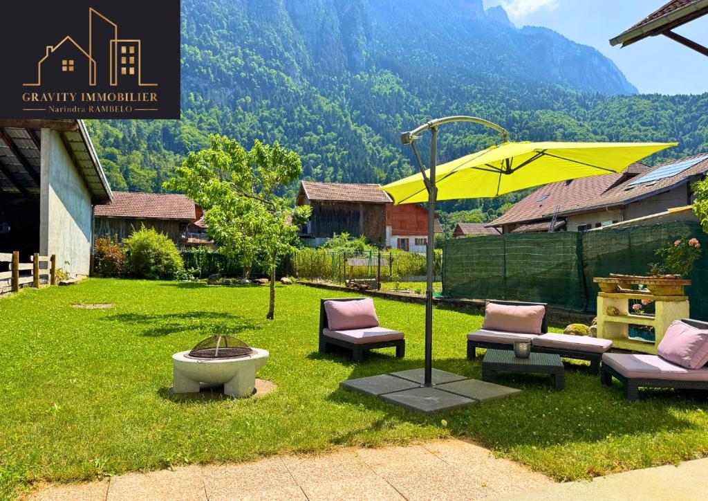 a group of chairs and an umbrella in a yard at Maison tout confort avec jardin in Bonneville