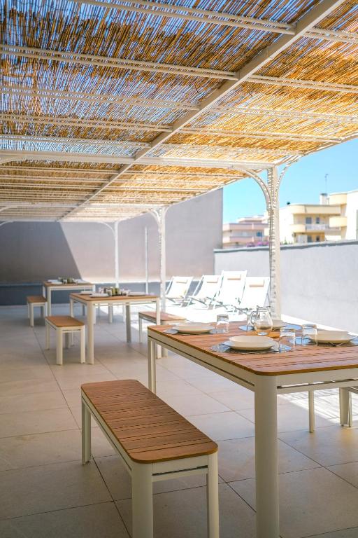 a room with tables and chairs and a straw roof at Dal Monaco - casa blu in Castellana Grotte