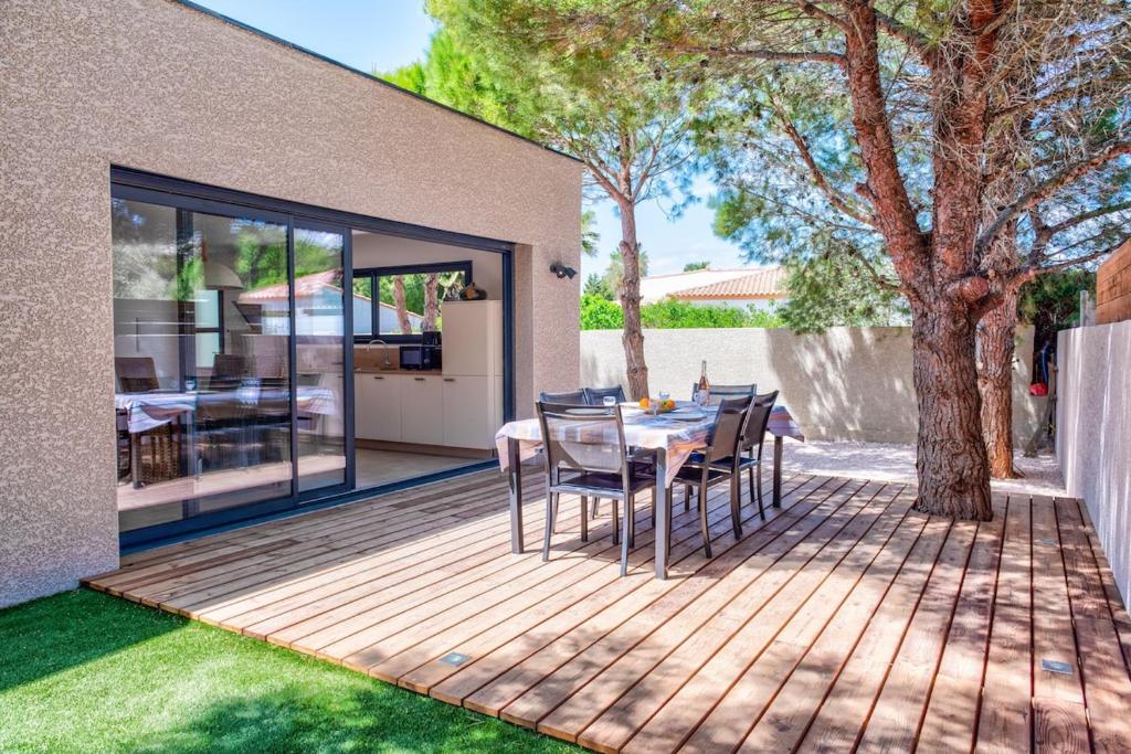 une terrasse en bois avec une table et des chaises. dans l'établissement Villa Louise, à Lapalme
