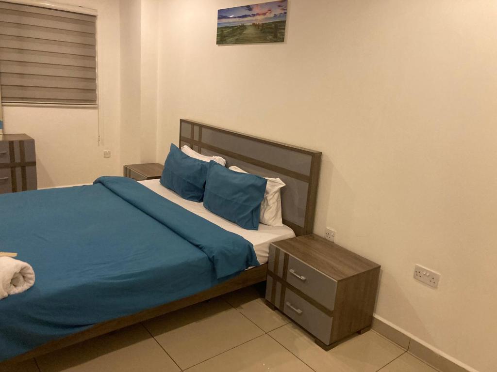 Un dormitorio con una cama con sábanas y almohadas azules. en The Gallery homes- two bedroom, en Madina