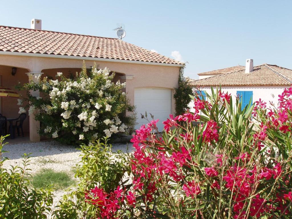 une maison avec des fleurs roses devant un garage dans l'établissement Family villa in Salles-d'Aude, à Salles-dʼAude