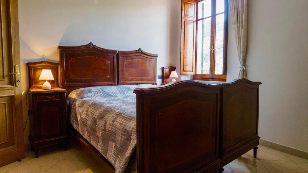 Un dormitorio con una gran cama de madera y una ventana en Casa Mirella, en Ameglia