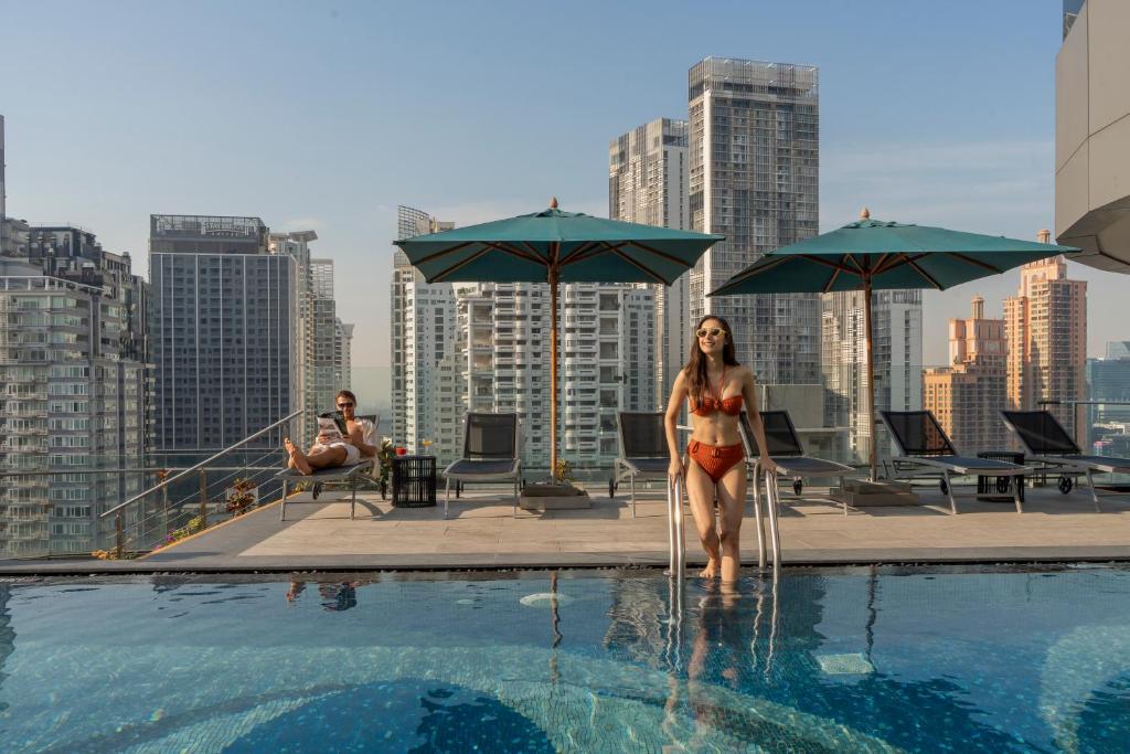 a woman in a bikini standing in a swimming pool at Hyatt Place Bangkok Sukhumvit 24 in Bangkok