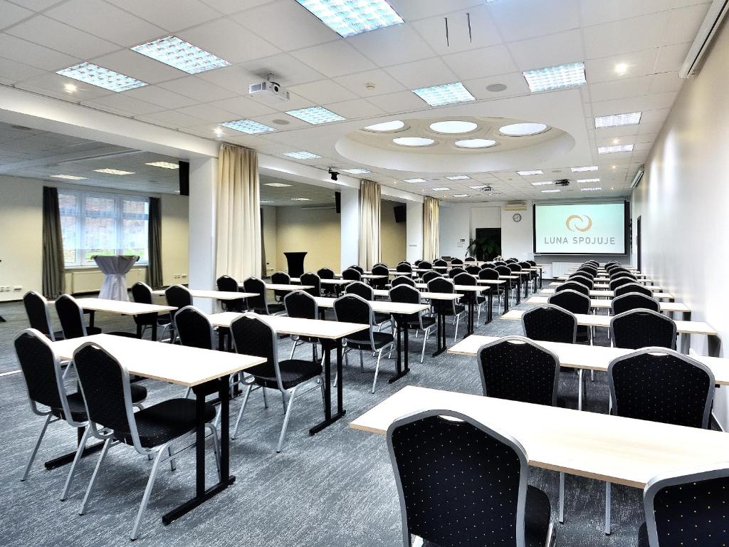 pusty pokój ze stołami i krzesłami oraz ekranem projekcyjnym w obiekcie Hotel Resort Luna w mieście Ledeč nad Sázavou