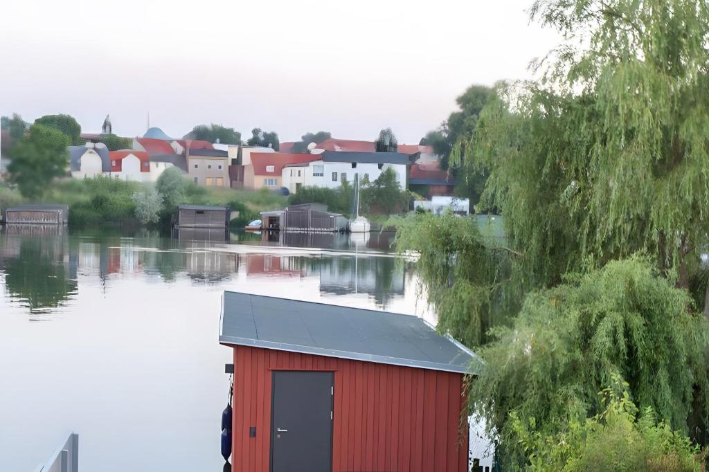 een rood boothuis aan een rivier met een stad bij Haus Seezeit in Malchow