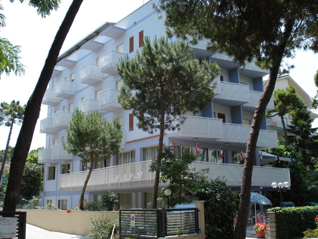 a white apartment building with trees in front of it at Hotel Singapore in Milano Marittima