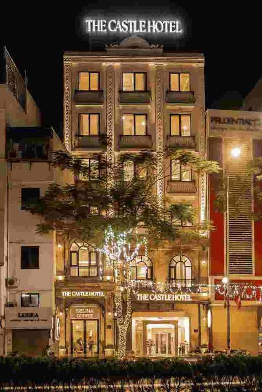 a building with a tree in front of it at Delina Castle Coffee & Hotel in Hanoi