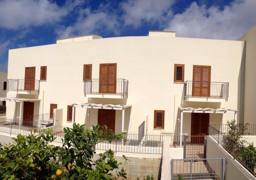 un grande edificio bianco con finestre con persiane marroni di Il Peperoncino a San Vito lo Capo