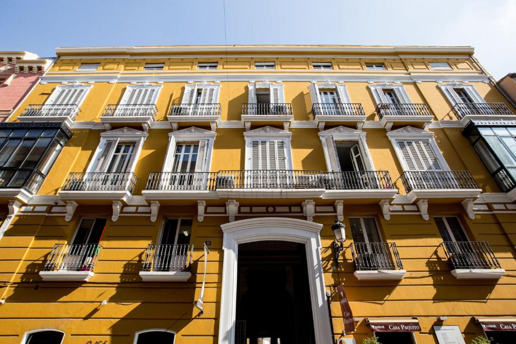 a yellow building with white windows and a door at Palacio de Rojas in Valencia