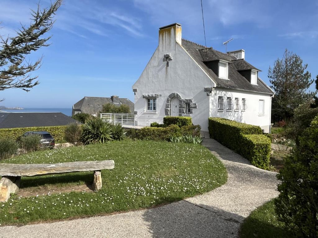 une maison blanche avec un banc devant dans l'établissement La Pastourelle - 10min à pied de la plage, à Saint-Cast-le-Guildo